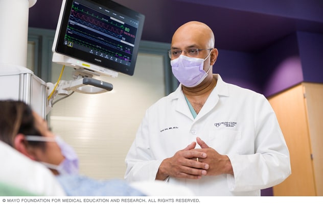 A doctor talks with a hospital patient at bedside.